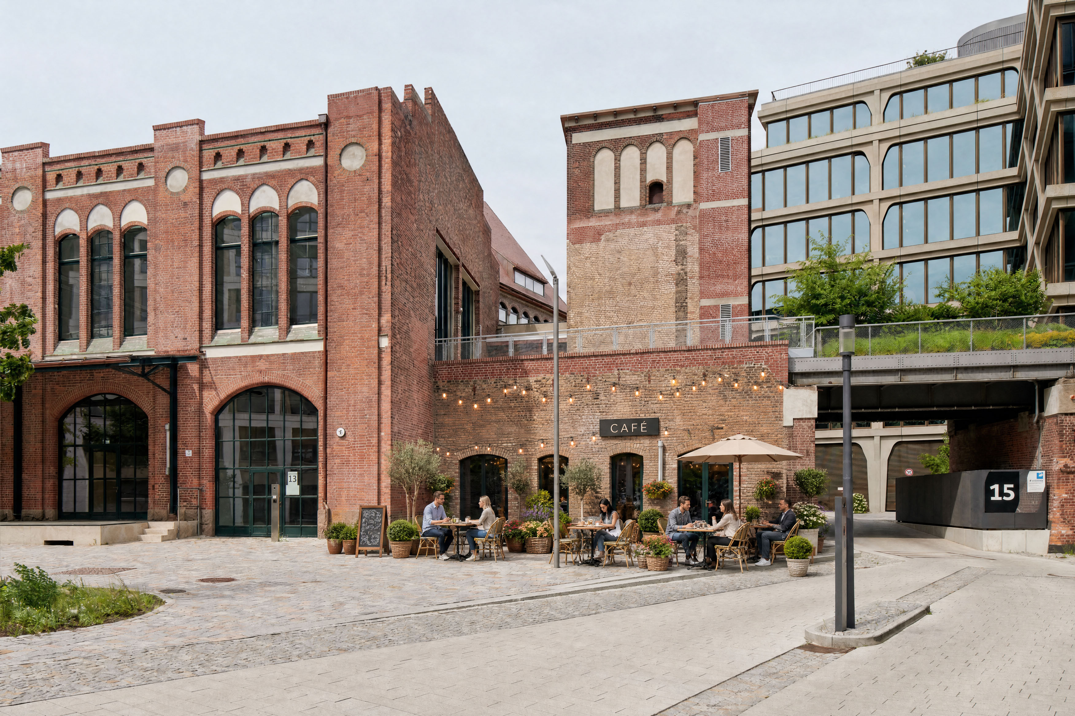 Café im Postbahnhof Berlin mit Außensitzplätzen vor der historischen Backsteinfassade und angrenzender moderner Architektur.