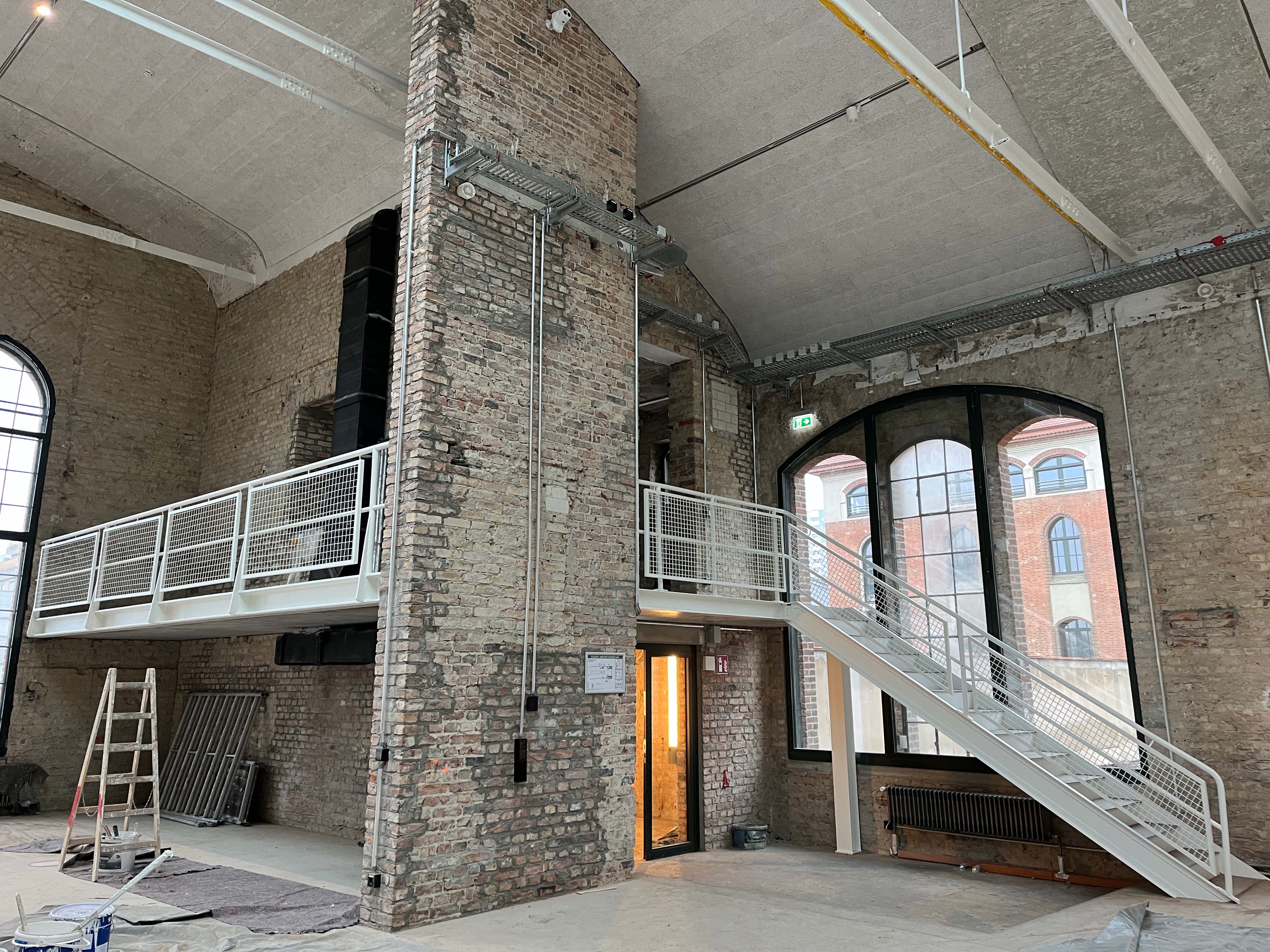 Eingangspackkammer mit Stützen, offenen Wandbereichen und Blick auf Fensterfassade.
