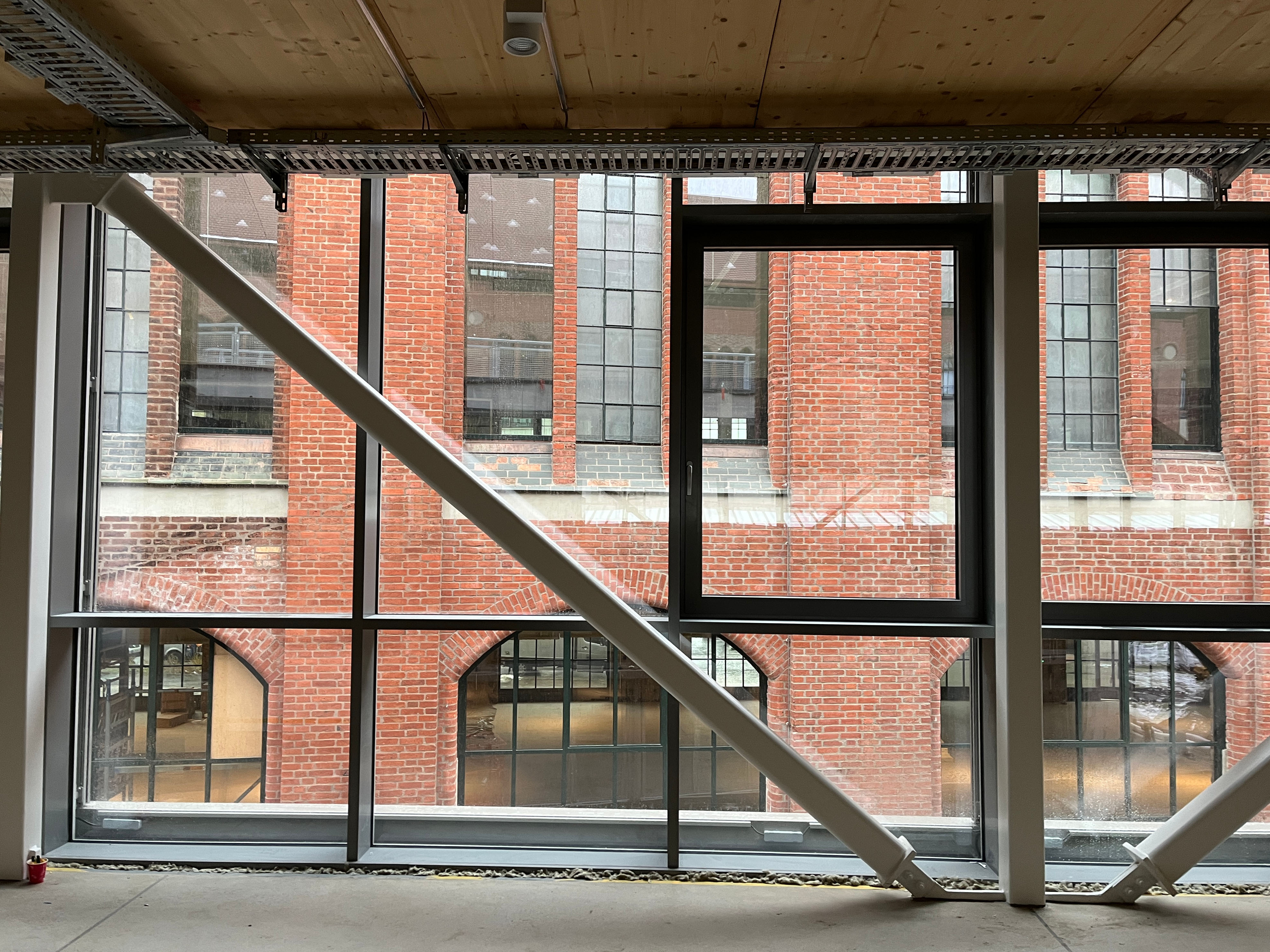 The construction progress at Postbahnhof Berlin shows the Beutel on the first upper floor with a window front featuring metal bracing and a view of a brick facade in the courtyard.