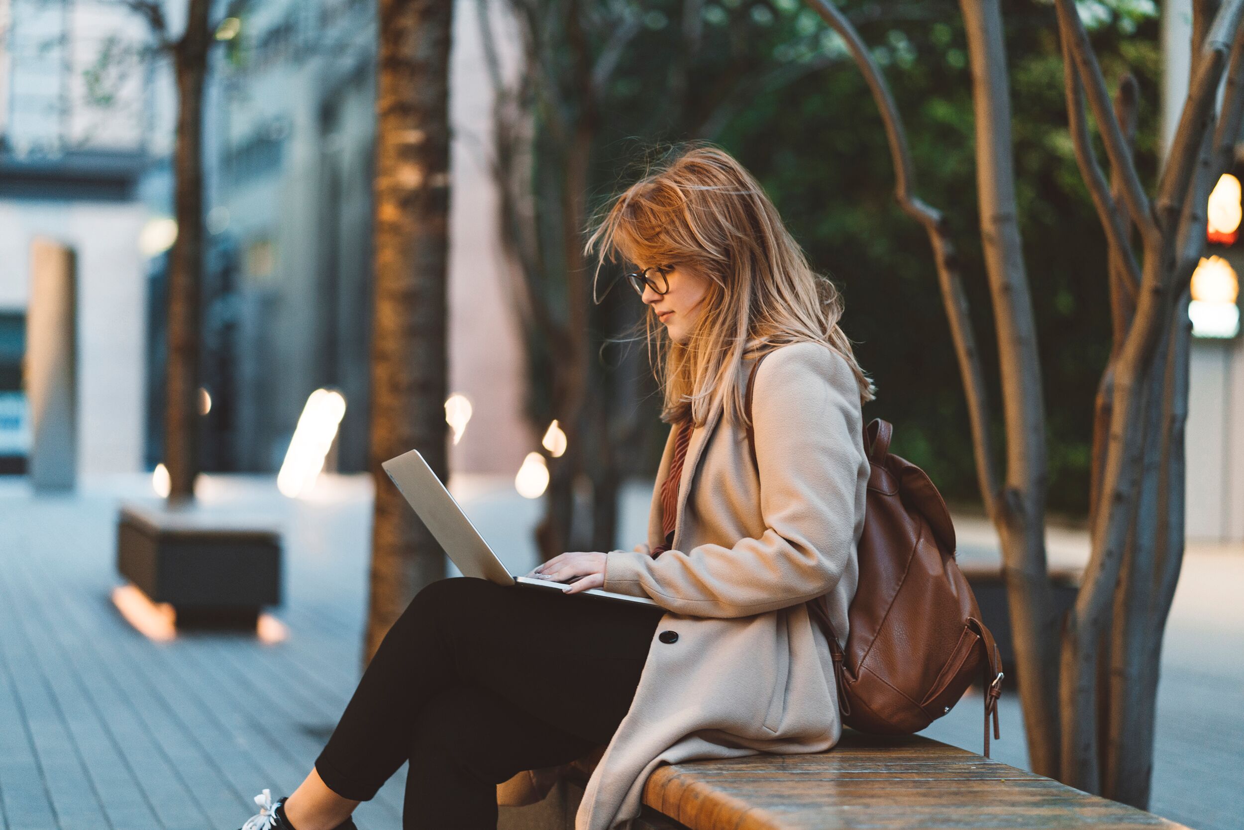 Kreative Arbeit im Freien, eine Frau tippt auf ihrem Laptop.