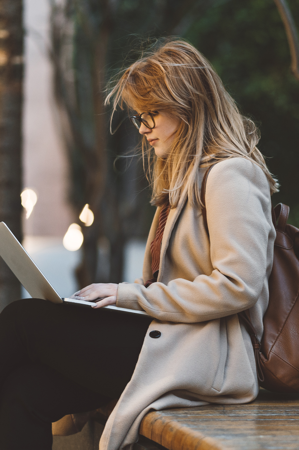 Kreative Arbeit im Freien, eine Frau tippt auf ihrem Laptop.