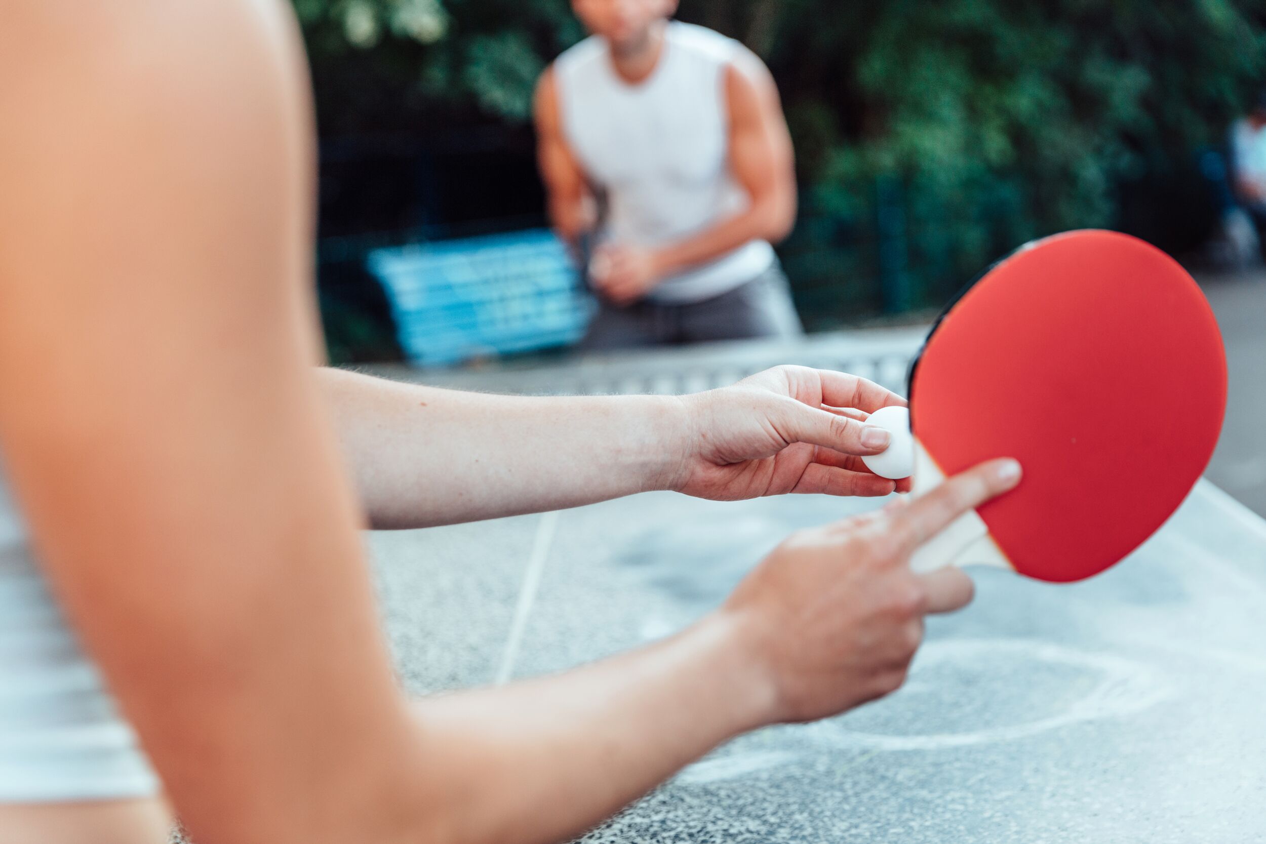 Zwei Personen spielen Tischtennis im Freien.