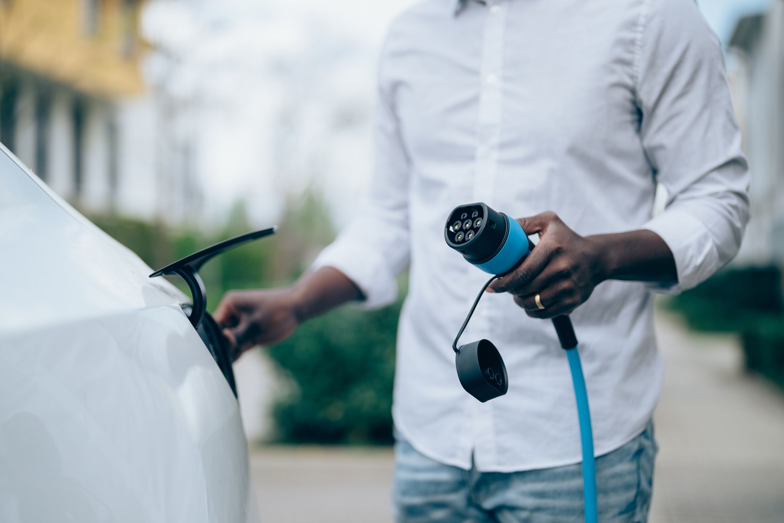 Mann schließt ein Elektroauto an die Ladestation an.