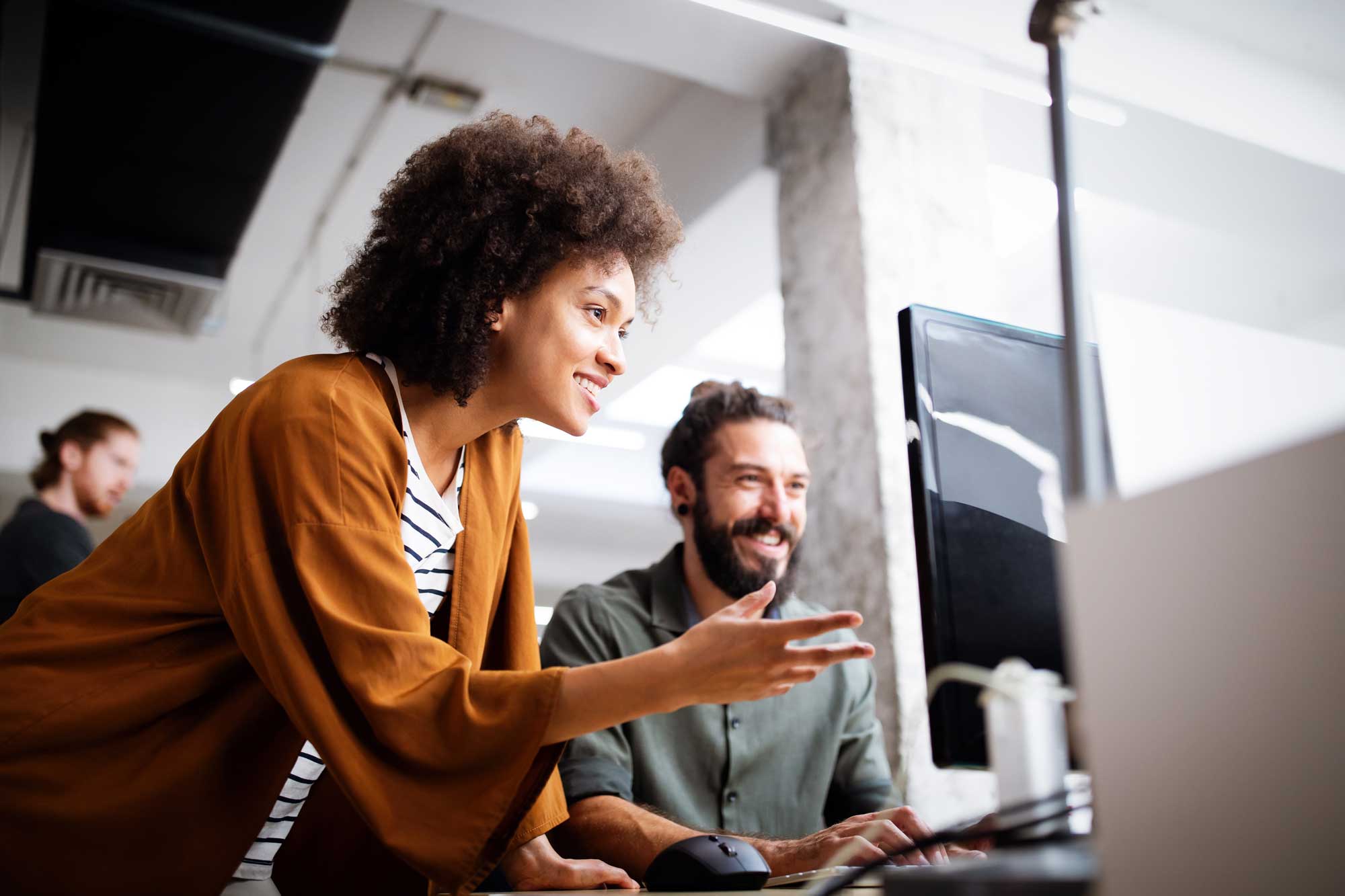 Zwei Personen arbeiten zusammen an einem Computer im Büro.