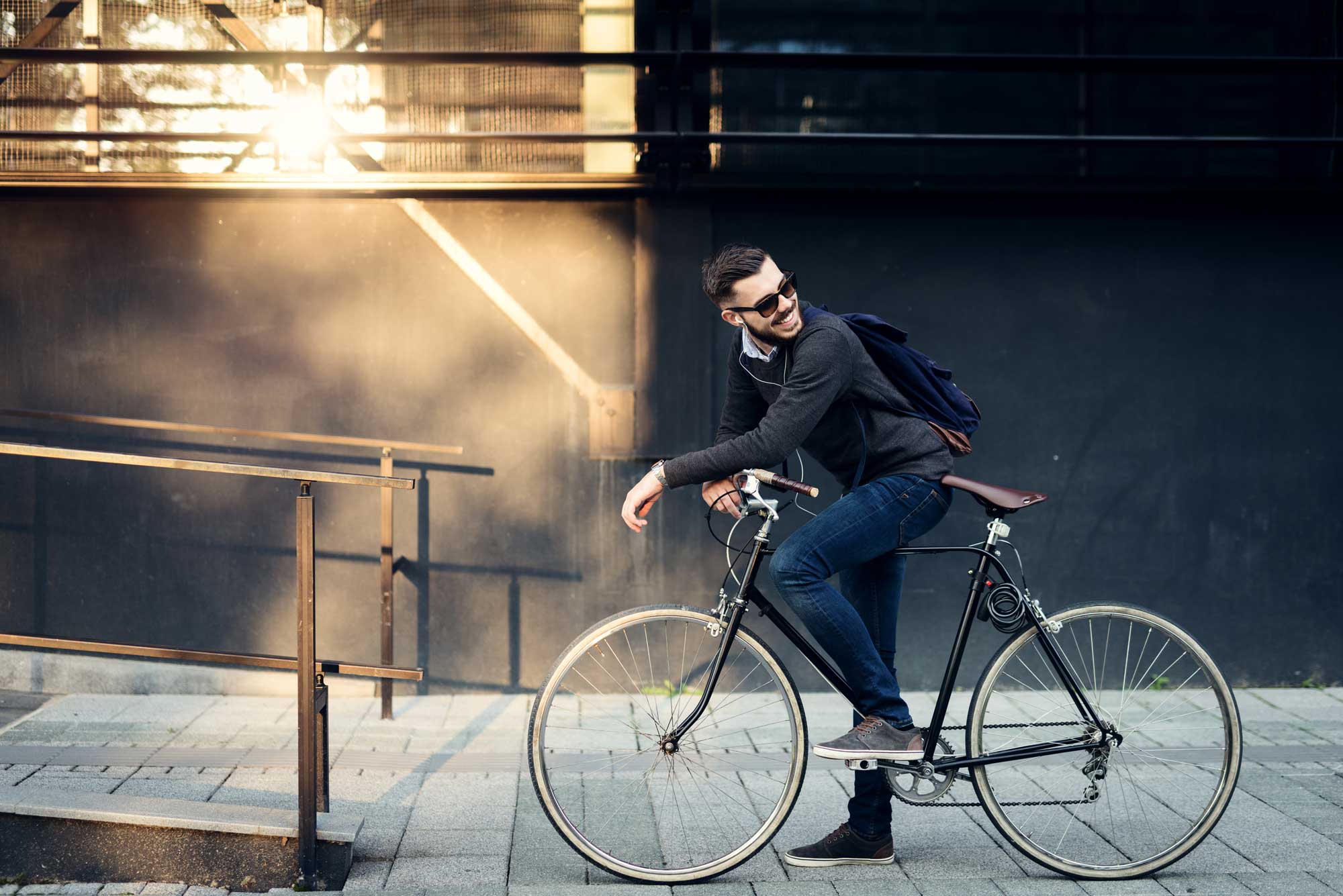 Ein stilvoller Mann mit einem Fahrrad und Rucksack auf dem Rücken.