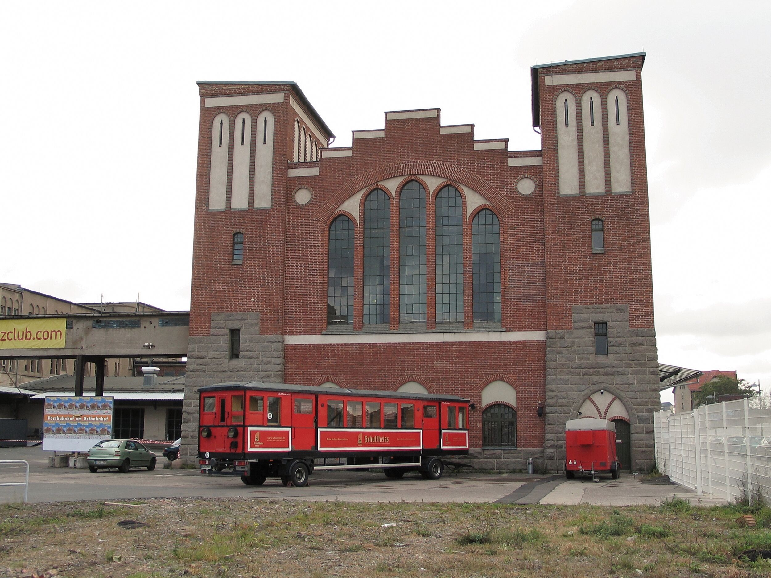 Roter Eisenbahnwagen vor Fassade des Postbahnhofs.